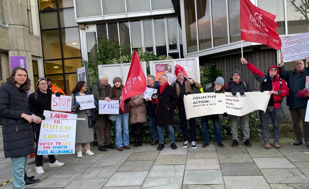 A picture of petitioners outside Hove Town Hall, waving signs, placards and flags, including Collective Action Brighton & Hove Saving the Winter Fuel Payment, Unite the Union and "stop pensioners dying".